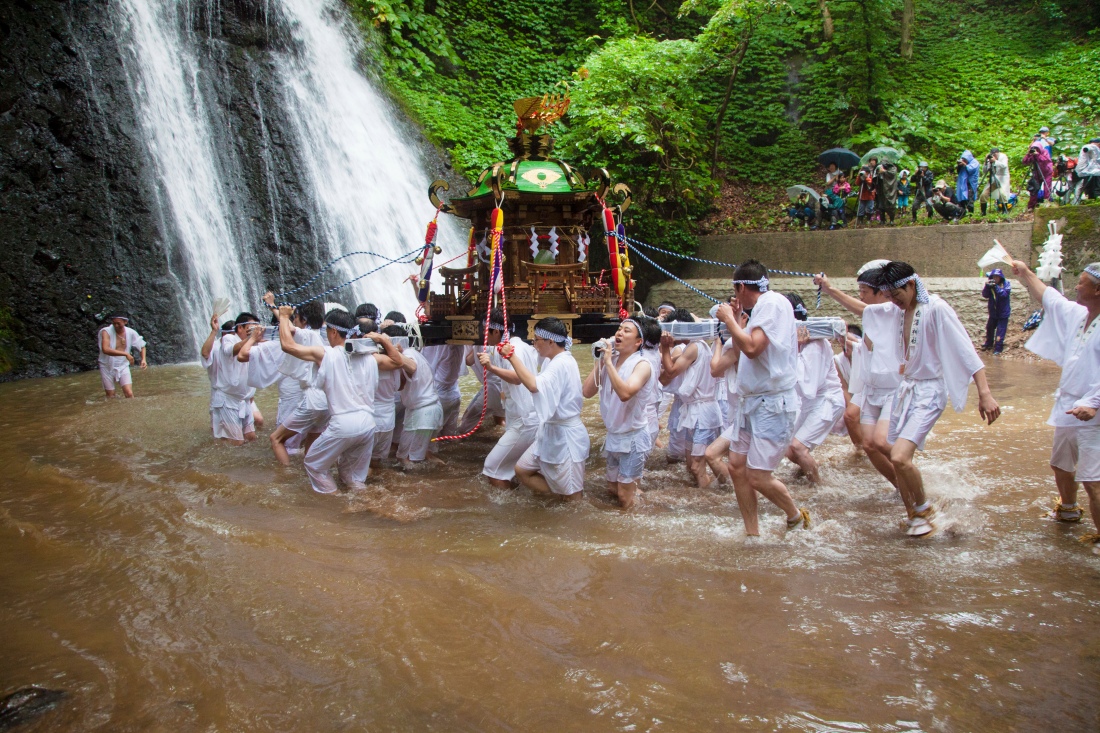 Local men carry the mikoshi into the waterfall.